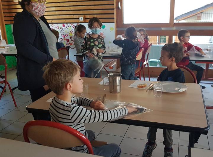 Le port du masque étant obligatoire à partir de 6 ans, les élèves le retirent uniquement à table, et le rangent dans une pochette rouge, la pochette verte contenant le masque propre à mettre après le repas.